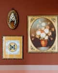 Vintage floral prints displayed on rust painted bedroom wall.