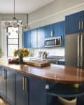 Blue cabinets in gray-painted kitchen with multi-armed pendant light hung over island.