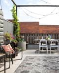 dining table with white tables in screened in patio with string lights