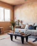 living room with warm textured paint walls, gray sofa, and pale neutral rug/carpet