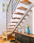Shoe storage under floating staircase in white room.