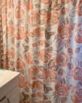 White bathroom with floral shower curtain and white and black framed mirror before makeover
