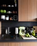 Kitchen with wood cabinets, black tile and countertops, green accents