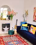 Blue velvet sofa topped with colorful pillows in colorful living room.