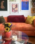 White living room with orange sofa, gallery wall, and colorful decor