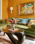 Yellow living room with green sofa and flowers on the coffee table