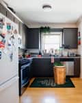 Kitchen with wood floor, black cabinets, wood floor, black and gray area rug, white walls