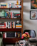 Bookshelf in art filled home office neatly organized, with various props dispersed throughout.