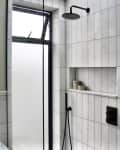 bathroom with vertical gray tiles, black hardware and accents, wet room shower