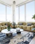 Living room with large gold cozy sectional, disco ball planters, marble round coffee table with flowers in vase, Lots of plants