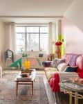 Colorful living room with red sofa, patterned throw pillows, large windows, pink, white, chartreuse, and lavender walls,  wood accent chair with shag throw, wood coffee table with books and colorful design objets