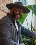 man tending to his houseplants by a window