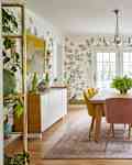 Formal dining room with whimsical, botanical wallpaper and long rectangular wooden table surrounded by yellow upholstered dining chairs.