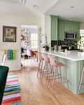 Pink stools surround green bar area in kitchen with white quartz countertops.