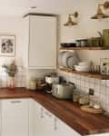 Sunny white kitchen with butcher block countertops and open shelving in newly renovated kitchen.
