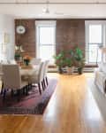 View of living room and dining room with exposed brick wall in background