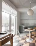 A round white dining table on a checkered floor between the living room and kitchen