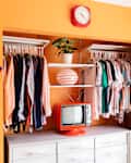 Orange painted wall in bedroom with vintage television on nightstand.