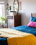 A bed with blue, yellow and pink comforters in a white bedroom.