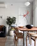 Black sofa with a marble-topped coffee table next to a wooden dining room.
