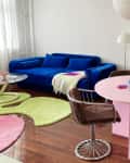 A pink tabling in a white-walled living room with four chairs and a book display stand.