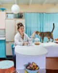 Dweller sitting at kitchen countertop petting cat.