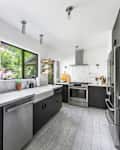 Black cabinets and marble countertops in light filled kitchen.