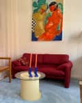 Colorful painting above red vintage sofa in studio apartment living room.