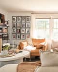 living room with large off-white sectional sofa with peach and warm hued pillows and throw, grid-style gallery wall
