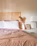 pale warm gray bedroom with subtle peach ombre painted on wall behind bed with rattan headboard