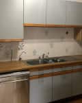 outdated smoke-stained kitchen with gray cabinets and white and blue tile backsplash before remodel