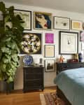 A bedroom wall with a gallery wall and a bed with blue sheets.