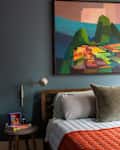 Large painting above neatly made bed.