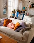 A white couch in the living room with colorful decorative pillows.
