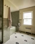 Black and white penny floors tiles in bathroom with green square tiles in shower.
