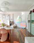 Rounded white table with pink Panton chairs and terracotta floors.