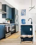 White kitchen with blue cabinets and blue and white art