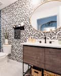 Bathroom with black and white gingko leaf print wallpaper and blue hexagonal tiled shower