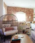 Brick-walled living room with white couch and decorative pillows.