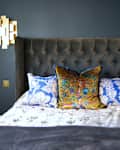 Bedroom with dark blue walls, geometric side lights, and decorative pillows.