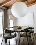 Red wood ceiling with large beams, giant white round paper lighting fixture, dark wood floors and dark wood modern dining table