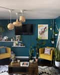 Teal and white living room with yellow armchairs and rattan pendant lights