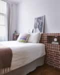 Brick walls in bedroom with neatly made bed.