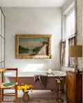 A pink claw foot tub across from a modern glass walled shower.