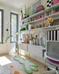 Brightly decorated home office with colorful shelves, modern desk, and unique rugs in green and pink.