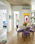 Round table and purple chairs seen in apartment with bedroom to the left and living room to the right.