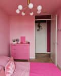 pink bedroom with pink bed, gallery wall, and pink dresser