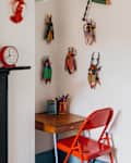 Small desk and red chair next to fireplace with blue bobbin mirror