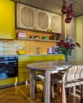 Yellow kitchen with fluted wood cabinets, parquet floor, window bar and dining table