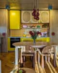Yellow kitchen with fluted wood cabinets, parquet floor, window bar and dining table